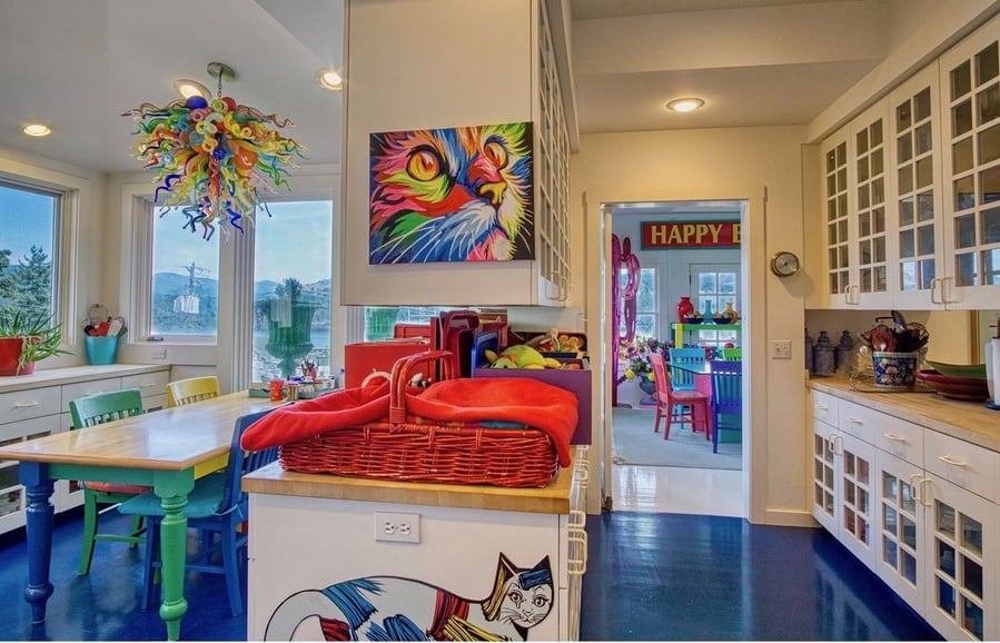 The Rainbow House's dining area continues the use of rich blue flooring and bright red accent pieces.