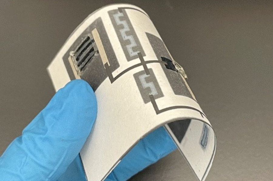 Researcher holds up an innovative paper circuit board that's naturally biodegradable.