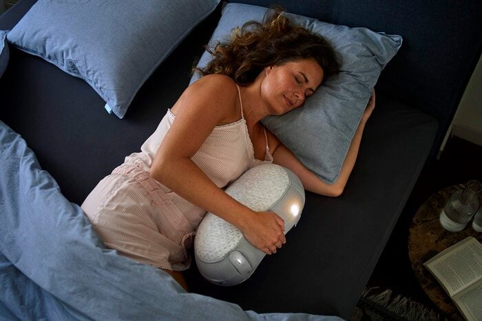 Woman sleeps soundly as she cuddles with her Somnox robotic pillow