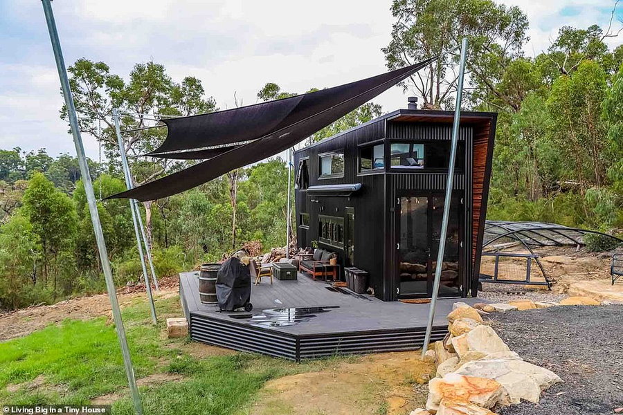 Large black deck coming off the back of the DIY tiny home gives the couple ample outdoor space. 