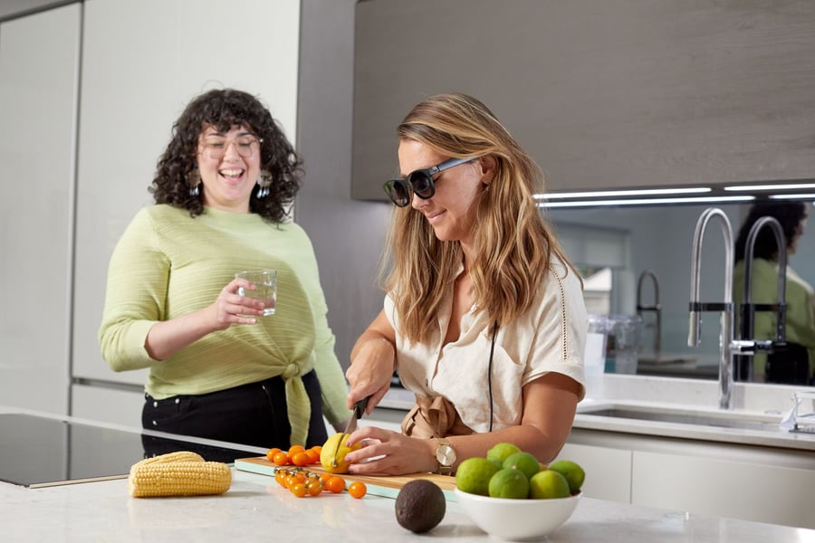 Deaf woman uses XRAI Glass to have a conversation with her friend without taking her eyes off the food she's preparing.