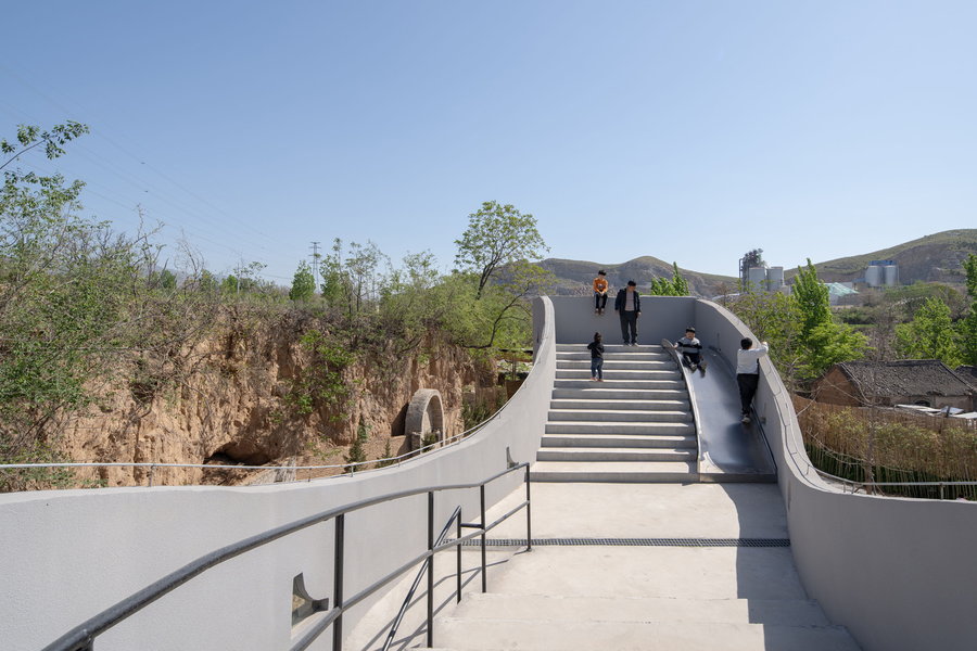 People walk along the concrete walkways on top of and around the Atelier Xi-designed 