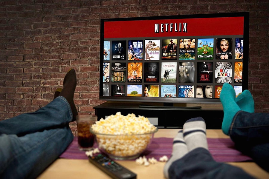 Couple watching Netflix at home over a bowl of popcorn.