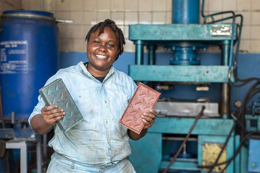 Nzambi Matee proudly holds up a pair of her super-sturdy recycled bricks. 