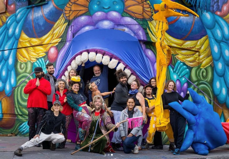Team behind Danaé Brissonet's monster puppet mural in Montreal poses in the large puppet mouth.