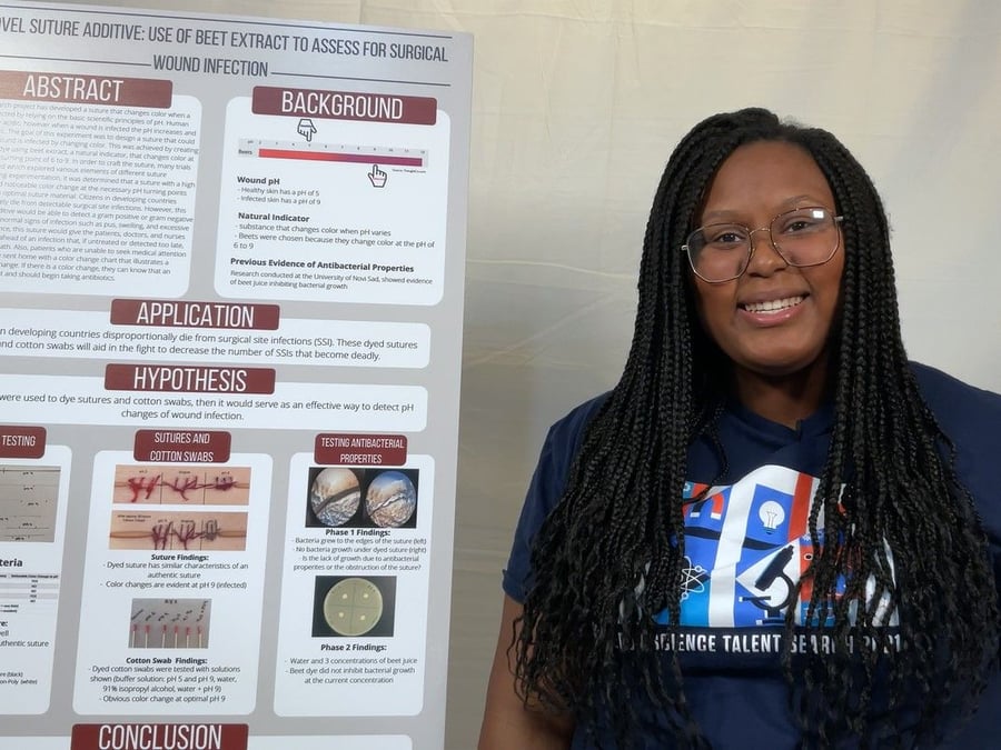 High school student Dasia Taylor poses next to a board explaining her color-changing stitch concept. 