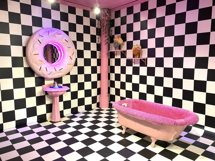Bold checkerboard bathroom in Fort Worth's Sweet Tooth Motel incorporates surreal busts and a neon doughnut mirror for a look that's totally carnivalcore. 