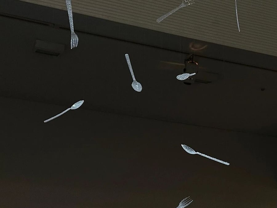 Perforated plastic utensils dangle from mid-air as part of Nina Nomura's 