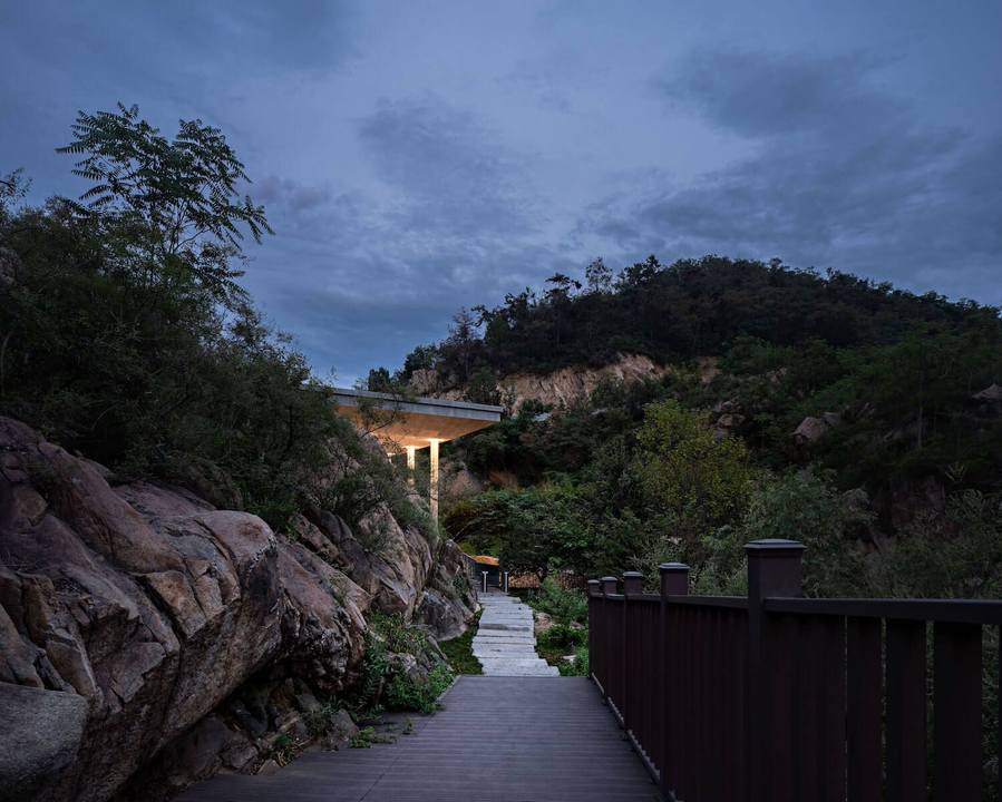 Nighttime view of the courtyard area leading up to the glowing chapel and reflecting pool.