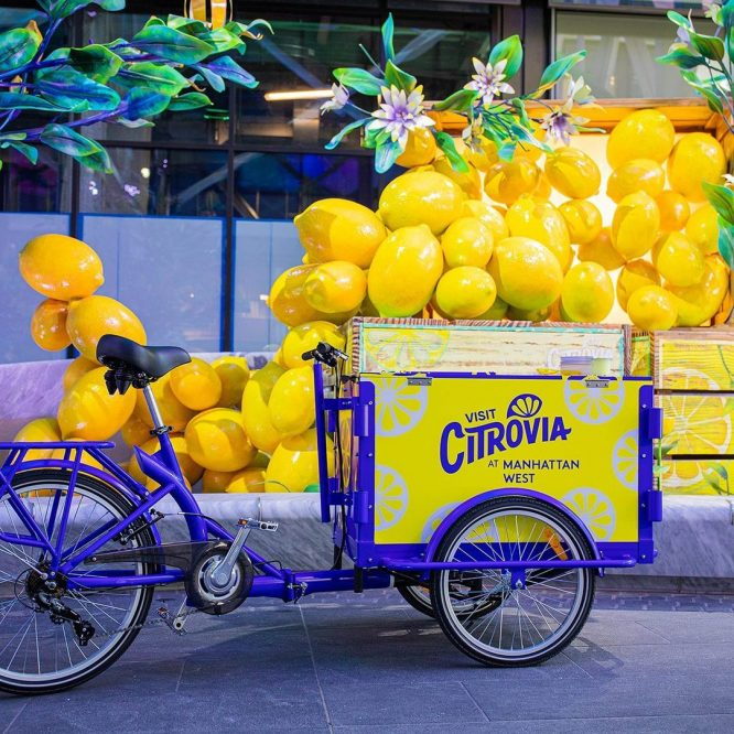 Vibrant lemon cart attached to a small bicycle, as featured in the Citrovia installation at Manhattan West. 