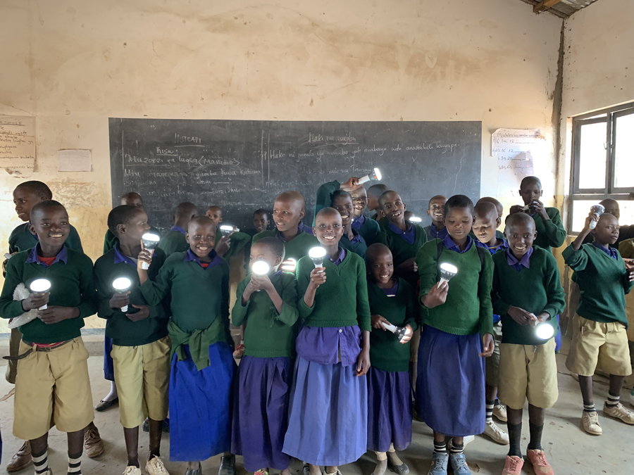 Tanzanian schoolchildren hold up solar flashlights charged using the miraculous Solar Cow.