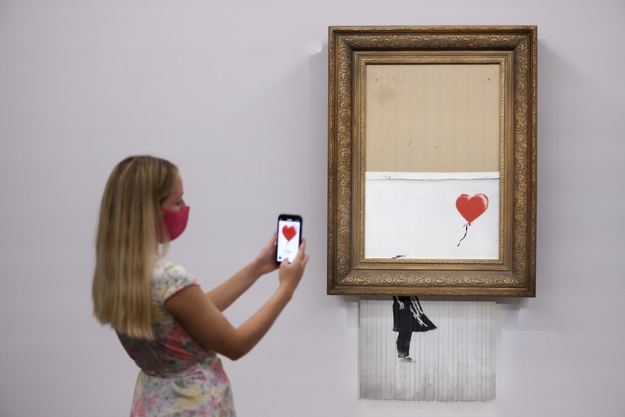 Girl snaps a picture of Banksy's half-shredded 
