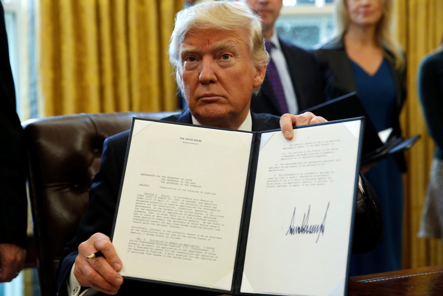 President Trump holds up a signed executive order.