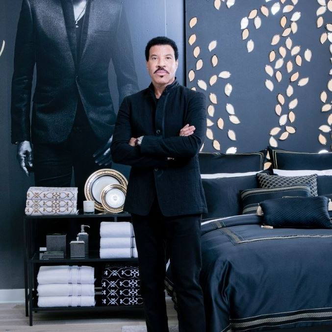 Lionel Richie stands by a bed sporting bedding he designed himself.