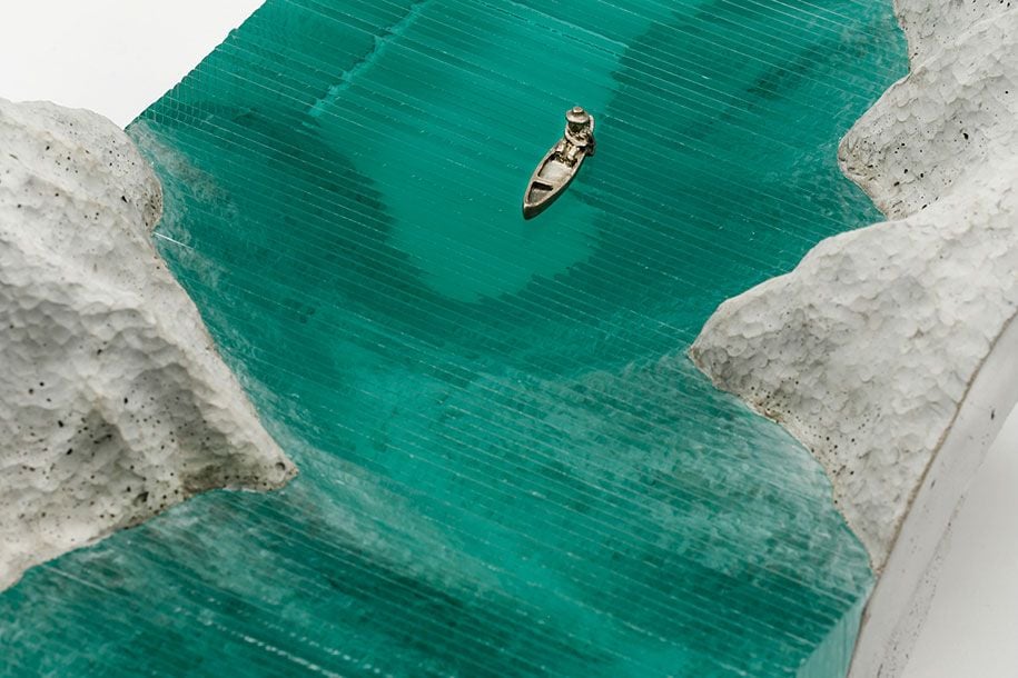 Close-up of a glass sculpture from artist Ben Young depicting a small row boat out on open water. 