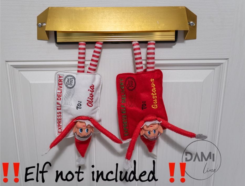 Two Elves on the Shelf pop out of a mail slot wearing personalized felt envelope costumes by Etsy user Damiline.