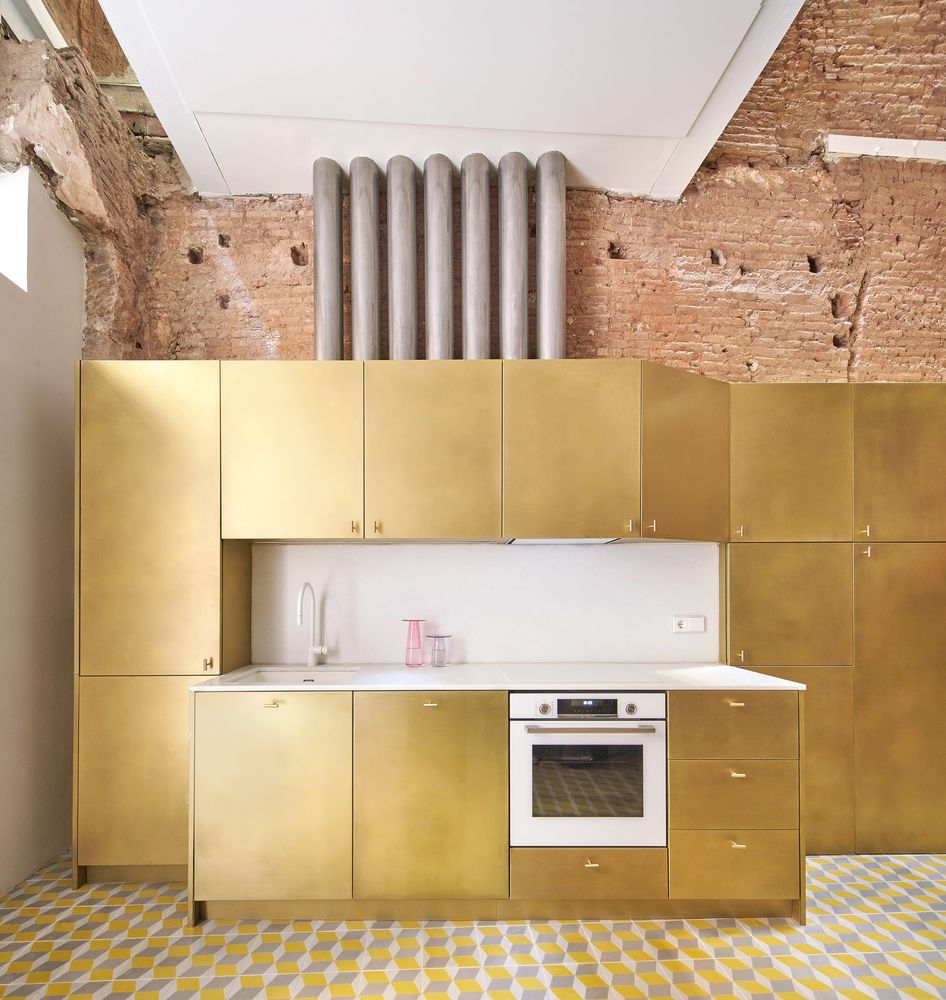 Gleaming brass kitchen space in Barcelona's renovated BSP 20 apartment.