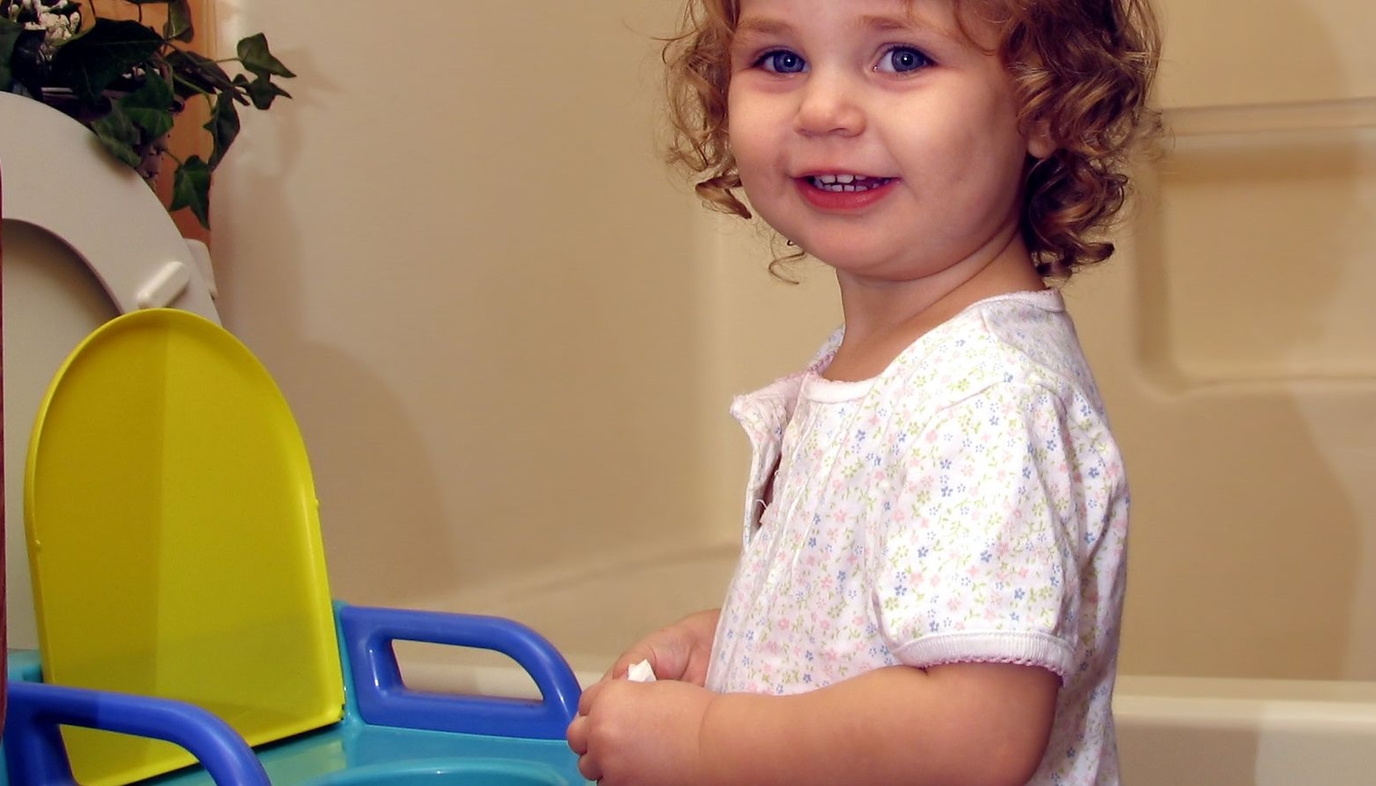 little girl standing by potty seat