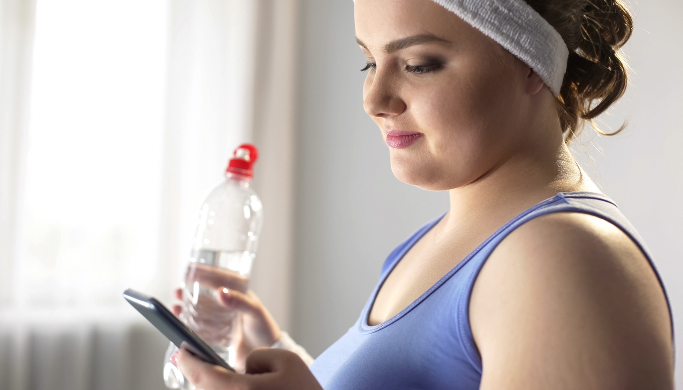woman wearing exercise clothes and looking at app on phone