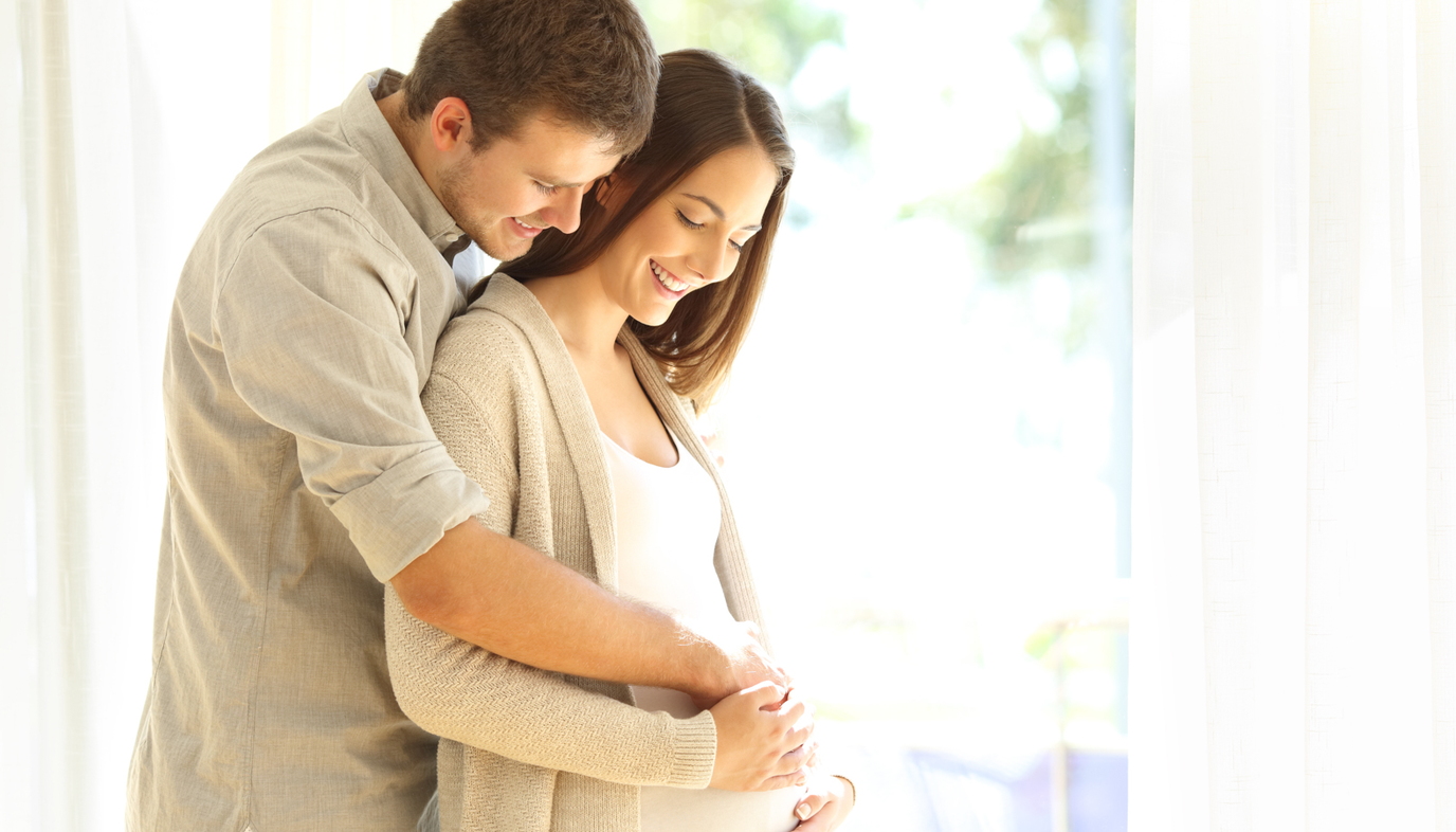 man with arms around pregnant woman