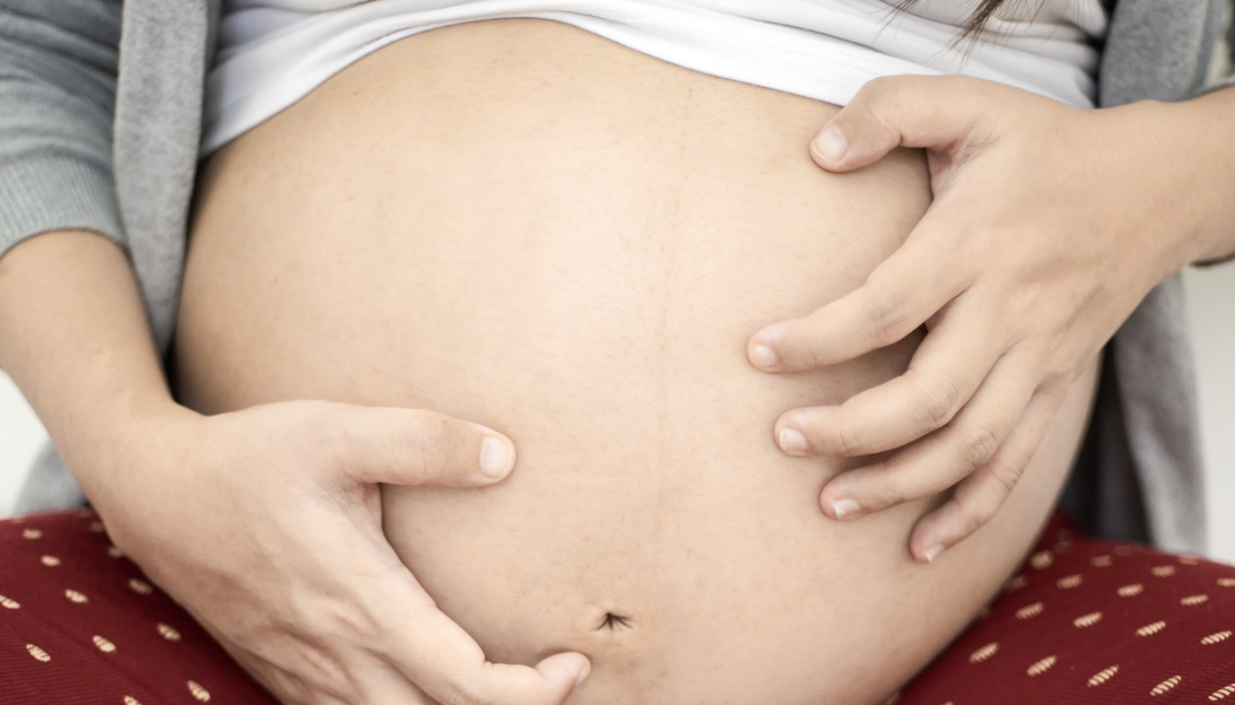 pregnant woman scratching belly