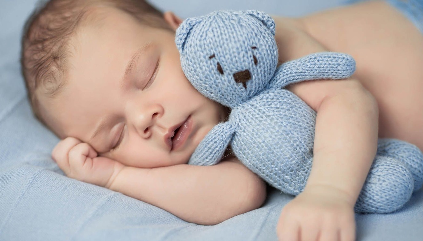 baby sleeping with blue teddy bear