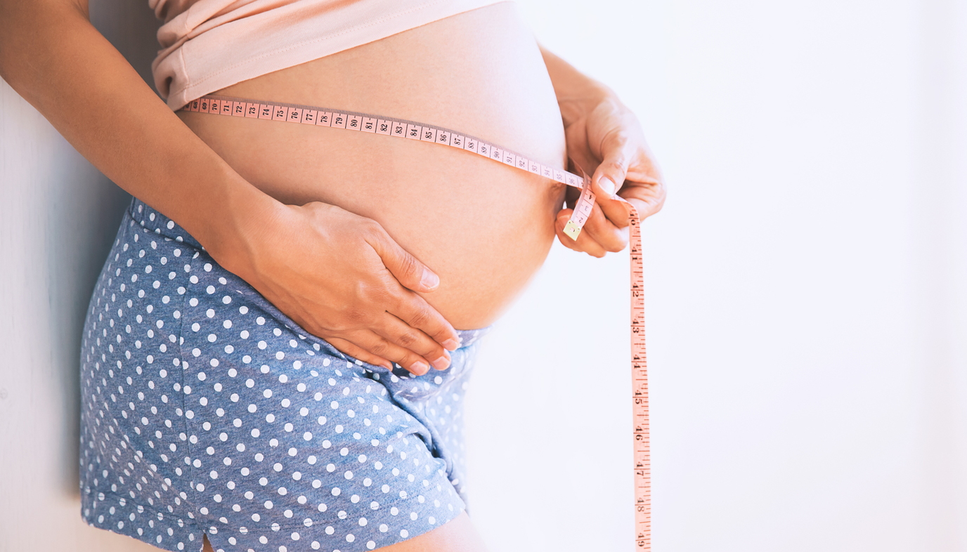 pregnant woman using measuring tape