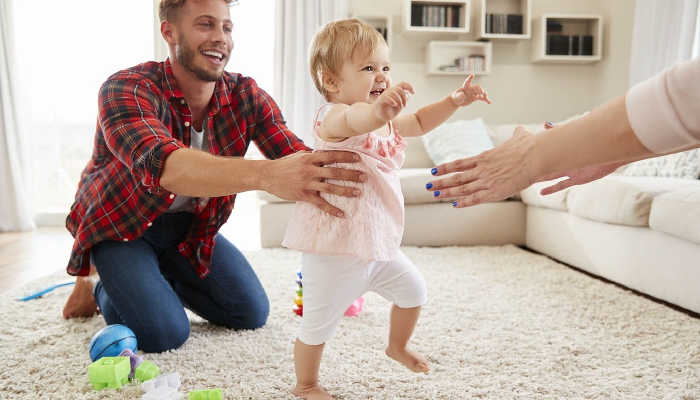 dad  helping baby walk to mom