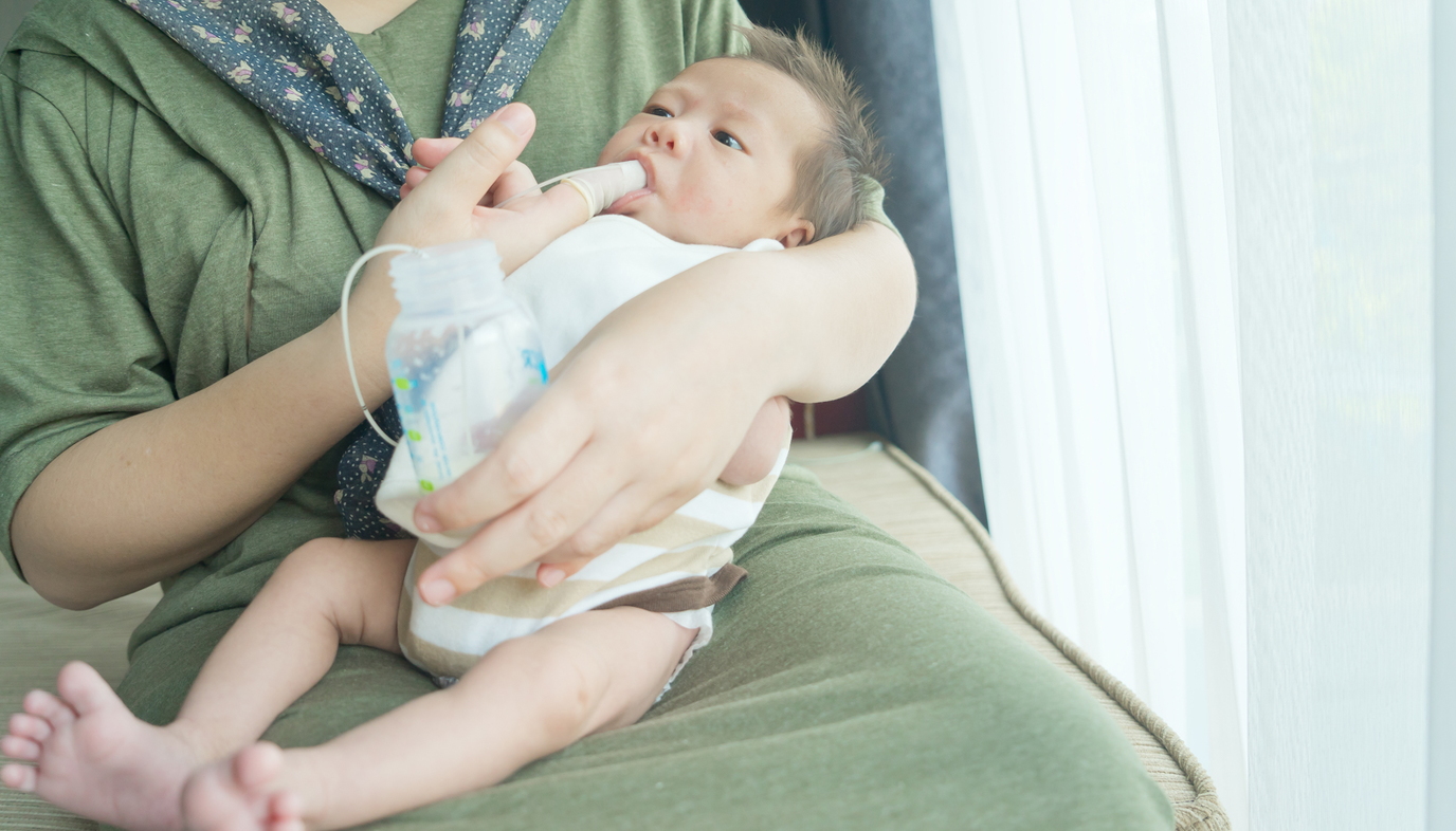 woman finger feeding baby