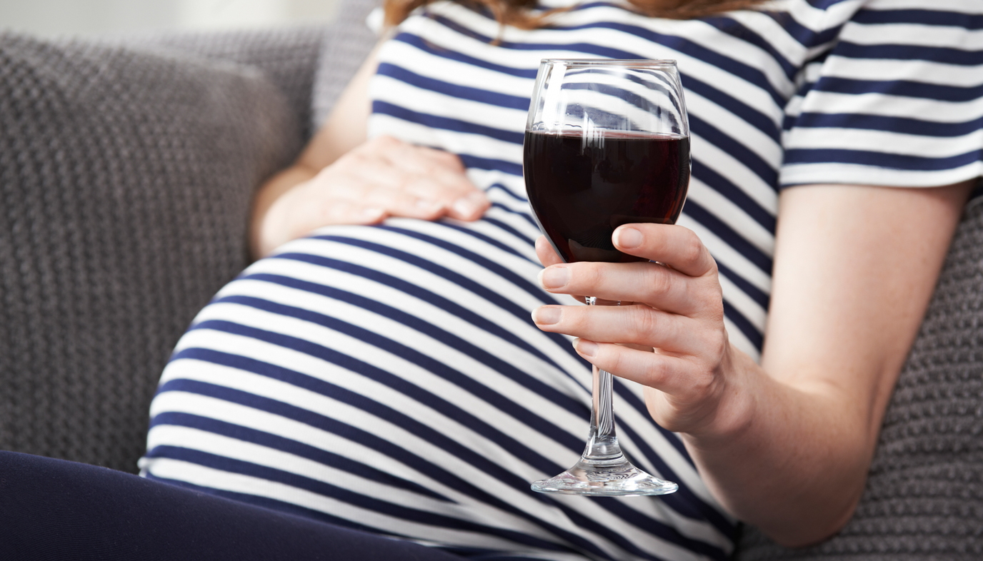 pregnant woman holding glass of wine
