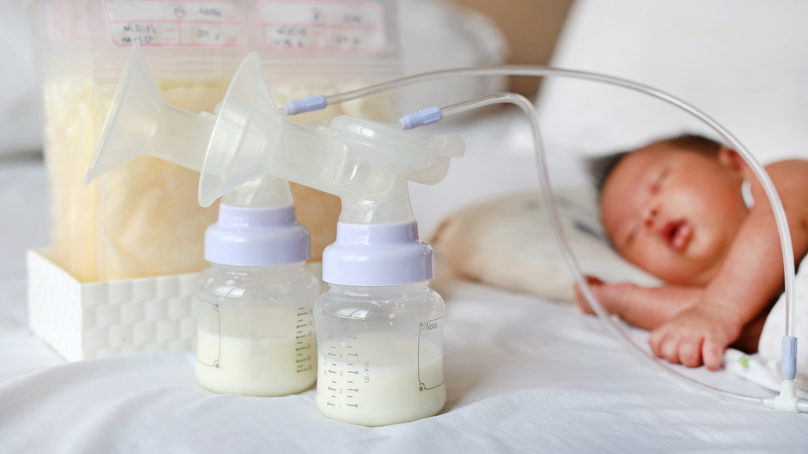 baby sleeping near pumped breast milk