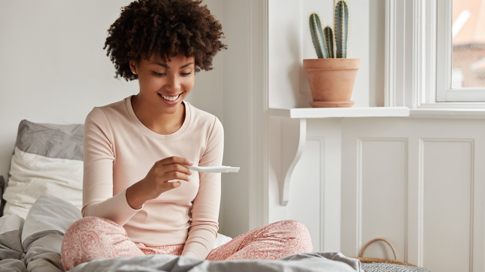 woman smiling at positive pregnancy test