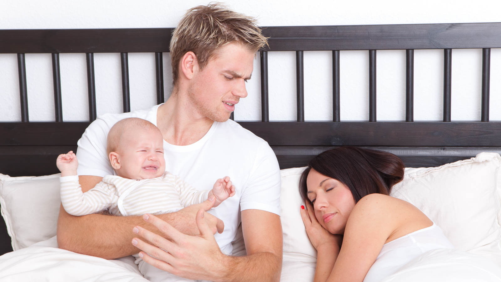 young couple in bed with baby