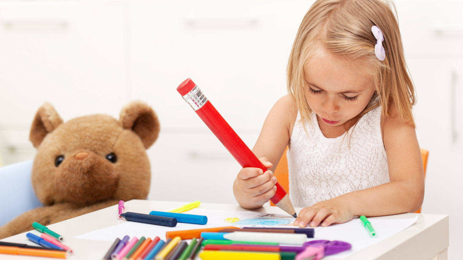 child writing with oversized pencil
