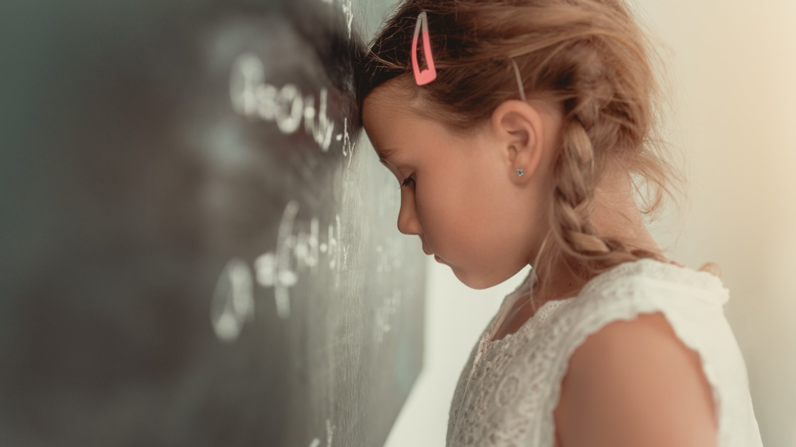 child with head leaned against chalkboard