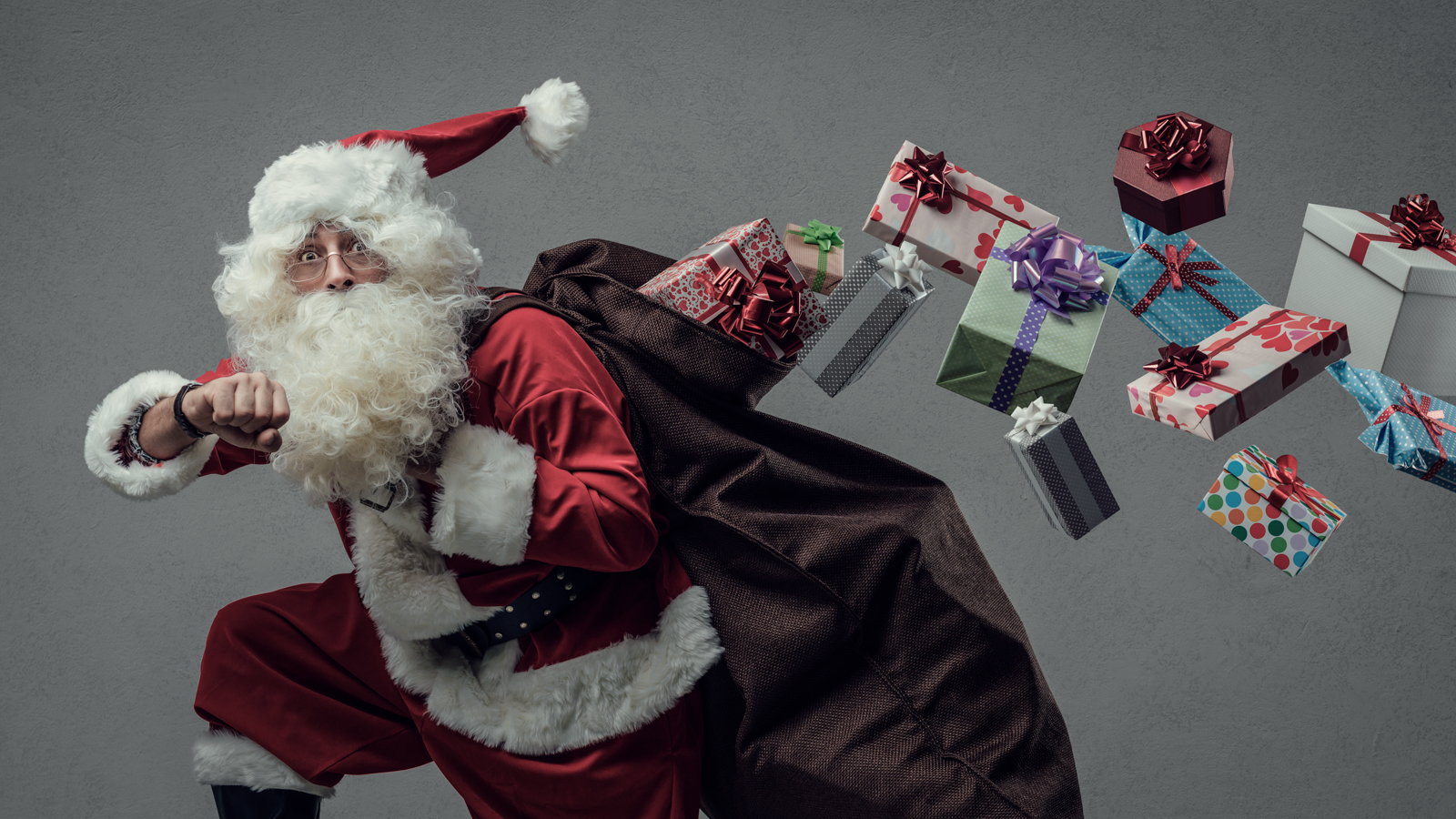 Santa Claus running with gifts flying out of bag