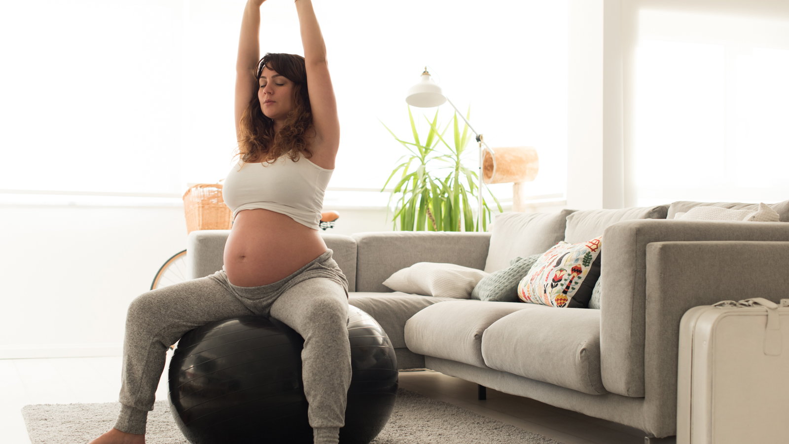 pregnant woman stretching on exercise ball