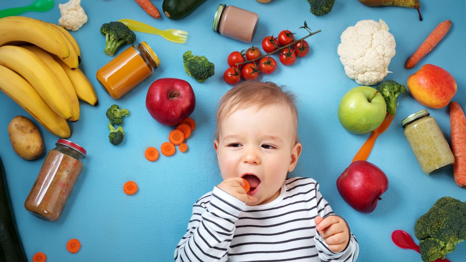 baby surrounded by fruits and vegetables