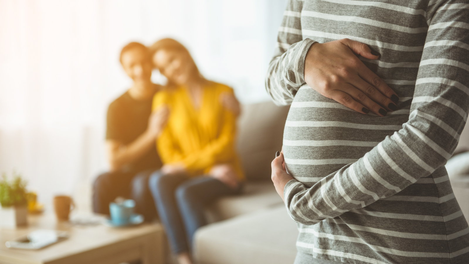 couple sitting on the couch looking at pregnant surrogant