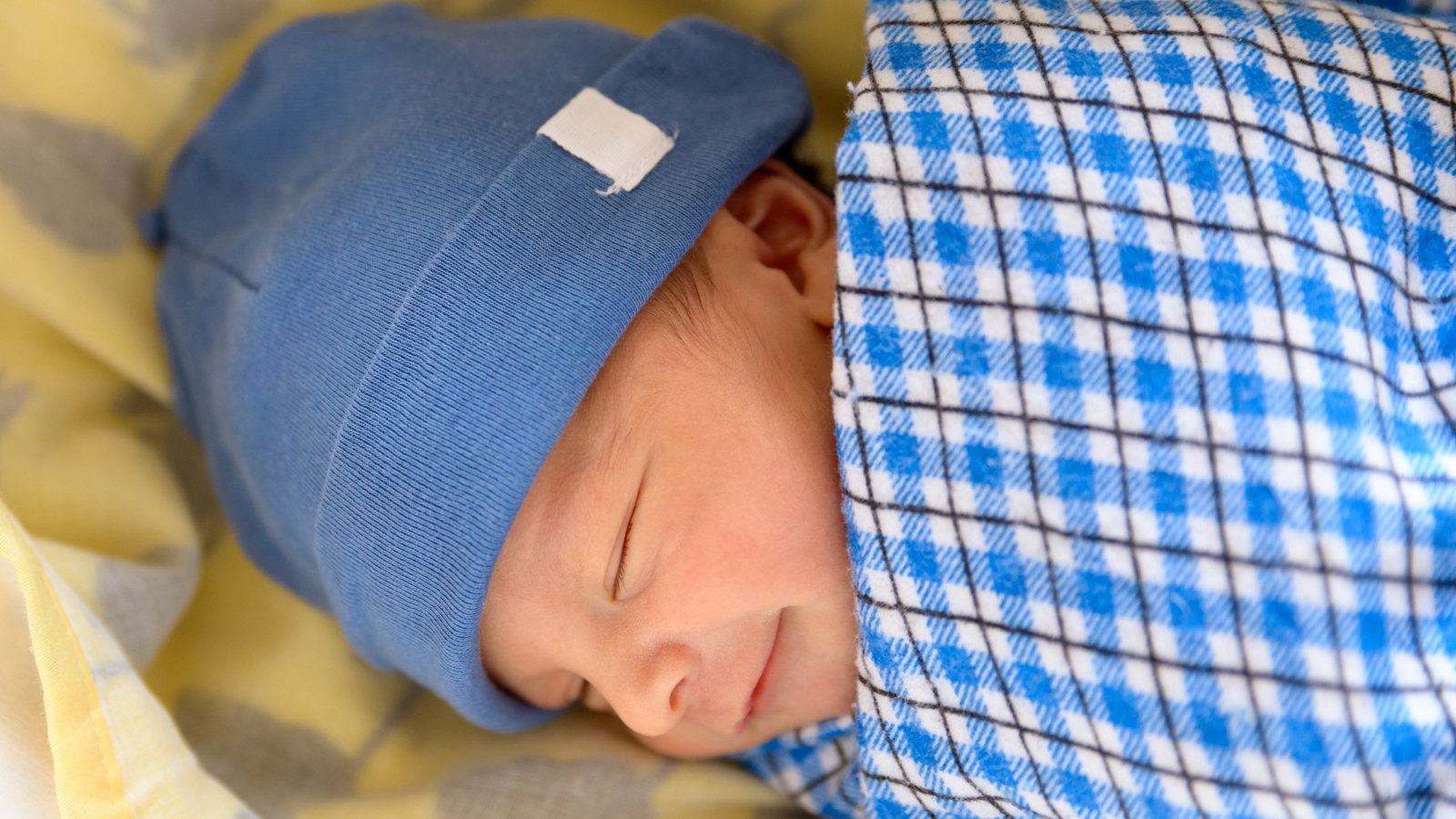 swaddled baby with a hat