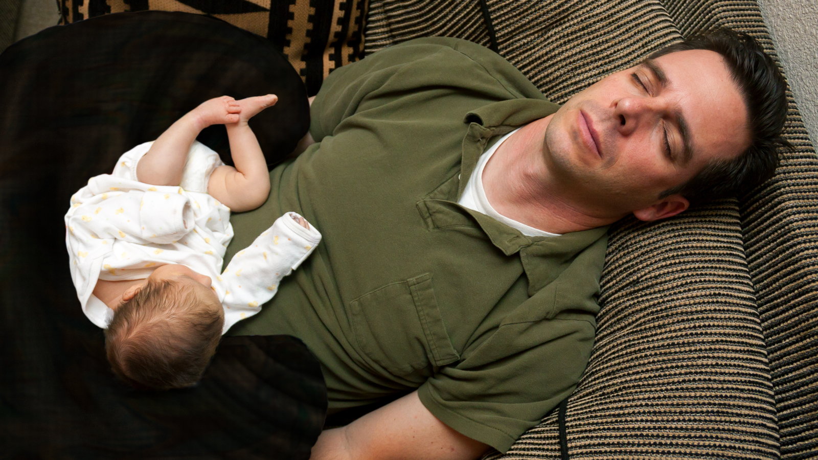tired father sleeping with baby on lap