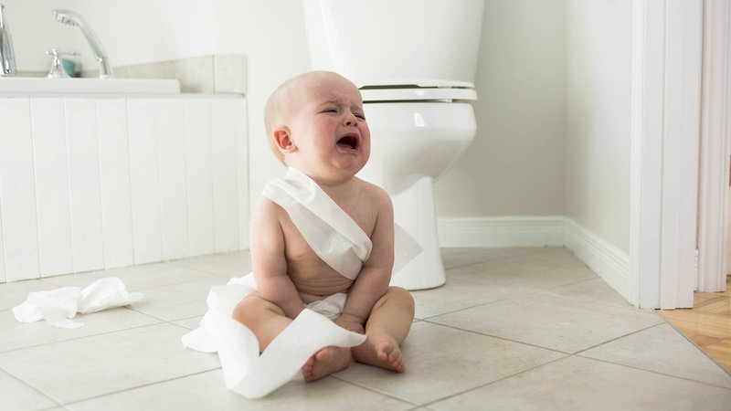 Crying baby wrapped in toilet paper on bathroom floor