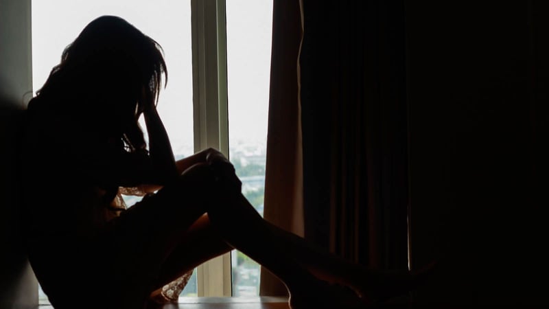 depressed woman sitting at window