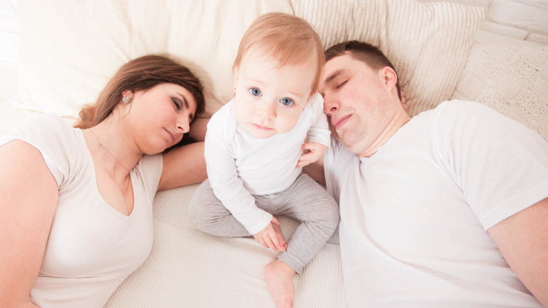 Sleeping parents with child awake