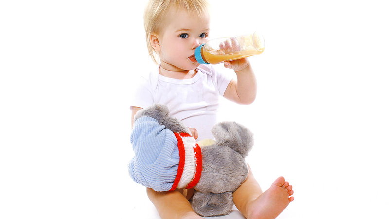 Baby drinking from bottle with stuffed anmal