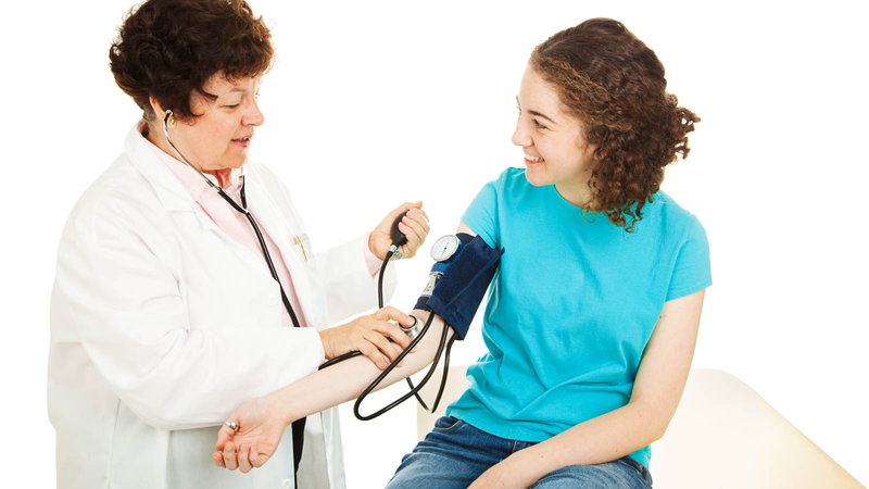doctor taking teenager's blood pressure