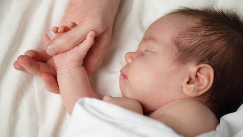Baby sleeping holding parents hand