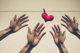 4 hands reaching for a heart