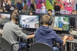 Two boys sit playing video games at a convention, unaware of the dangers of gaming disorder.