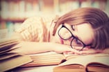 girl sleeping on top of pile of books